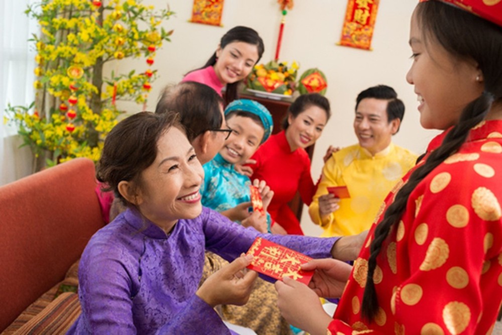 Donner l''enveloppe rouge - lì xì aux enfants ou aux personnes âgées est une coutume traditionnelle pour souhaiter la chance, la santé et la prospérité à celui qui la reçoit.